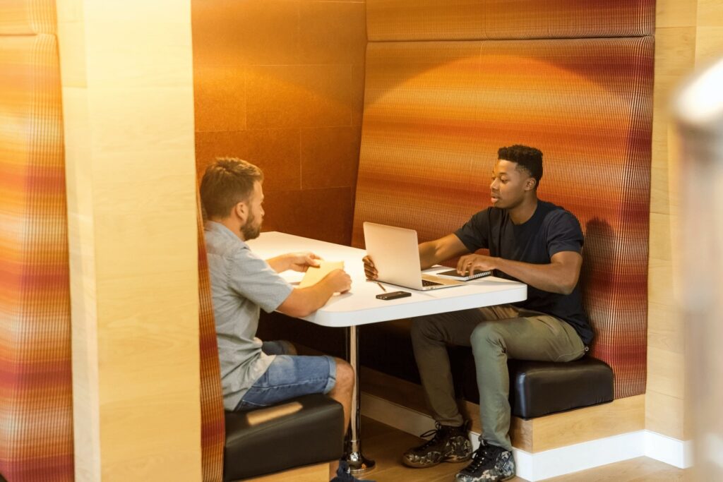 Anklyticx - Two men sitting at a table with laptops.