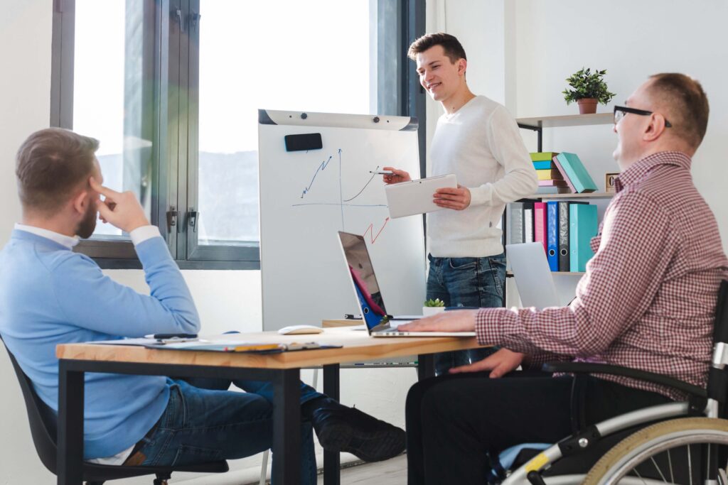 Anklyticx - A group of people in a wheelchair sitting at a table in an office.