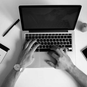 Anklyticx - A black and white photo of a person typing on a laptop.