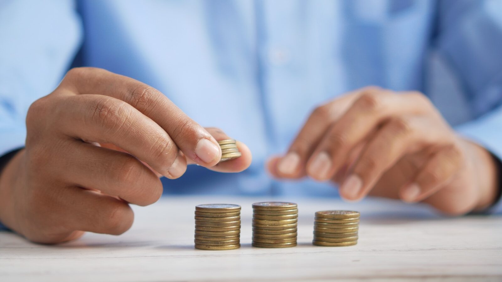 Anklyticx - A man is putting coins on top of a stack of coins.